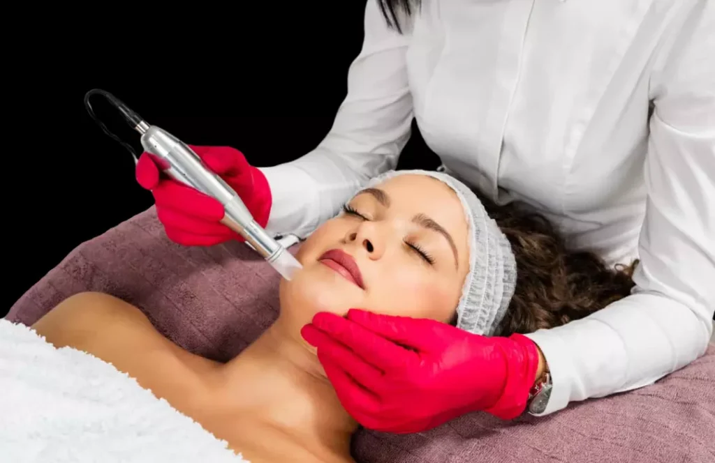 Woman receiving a facial treatment with a handheld device at The Better Body Shop LLC, Houston, TX, performed by a professional wearing red gloves.
