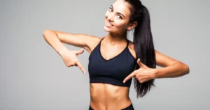 Woman smiling and pointing to toned abs, representing results from Non-Invasive Laser Lipo in Houston, TX.