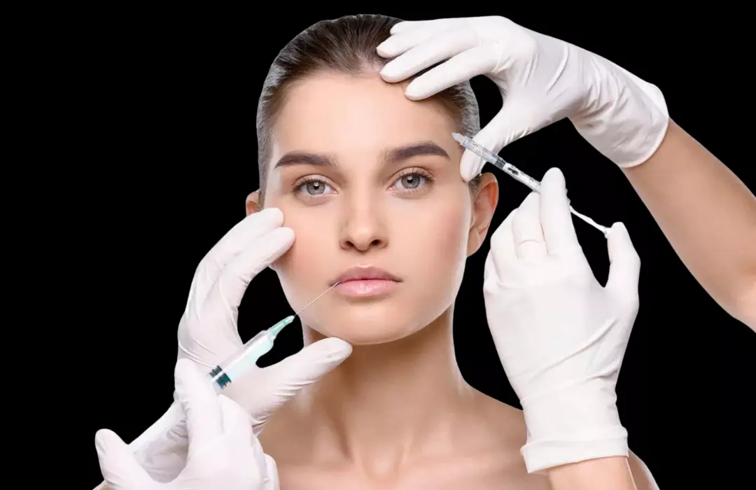 Woman receiving cosmetic injections in lips and forehead by medical professional wearing white gloves.